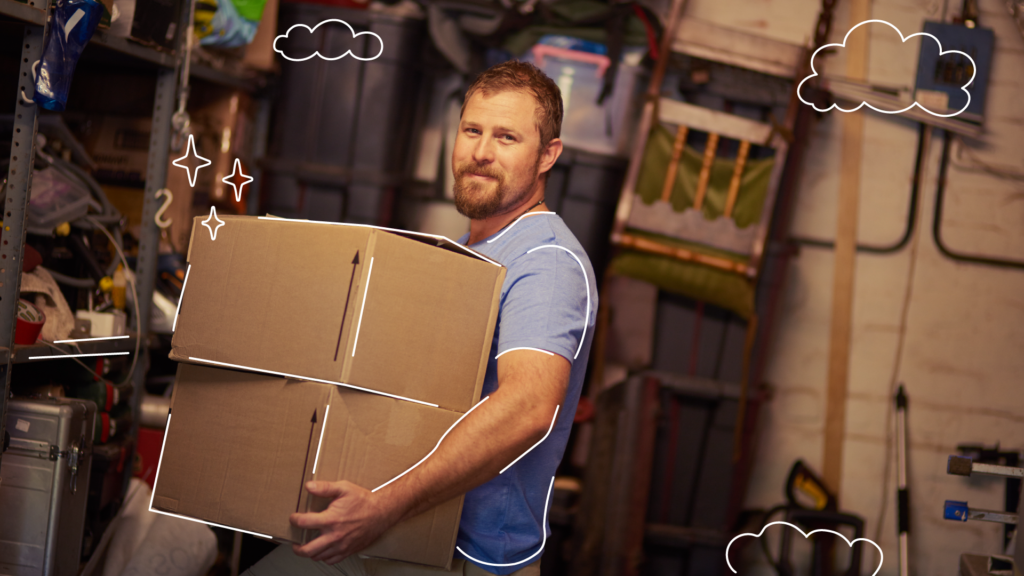 Man holding two cardboard boxes in his garage, a starting point for ADU conversion.